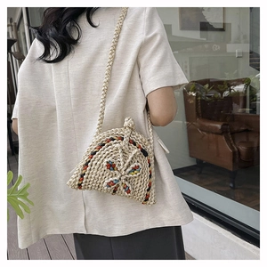 Détail de ce sac à bandoulière tissé avec des motifs colorés et un nœud décoratif