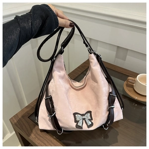 Détail du sac hobo rose avec nœud argenté et bandoulières réglables en cuir marron foncé