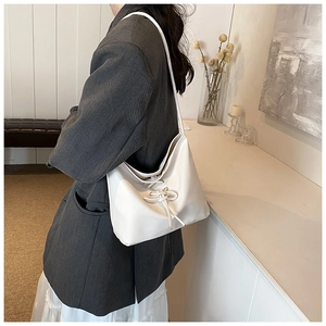 Vue latérale d'un sac seau blanc style ballet avec nœud à cordon sur l'épaule d'un mannequin