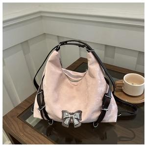 Détail du sac en velours rose avec nœud en métal argenté et anses en cuir marron