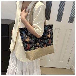 Detailed close-up showing vibrant butterfly embroidery on a black canvas tote bag