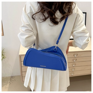 Close-up of royal blue asymmetric handbag with gold text detail and leather strap