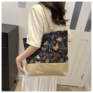 Detail view of large tote bag with butterfly tapestry and beige canvas worn on shoulder