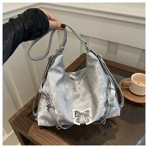 Détail d'un sac cabas argenté avec nœud métallique et bandoulière réglable en situation