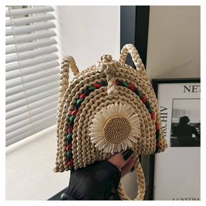 Détail d'un sac bandoulière en paille tissée avec fleur de marguerite et rayures colorées