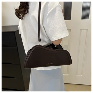 Detail of a dark brown asymmetrical shoulder bag with golden FASHION lettering text