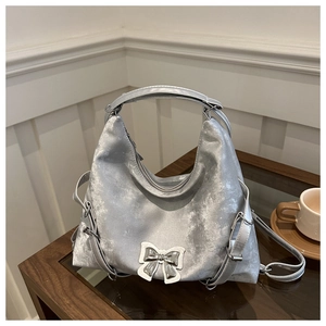 Détail du sac hobo argenté avec un nœud métallique sur un tissu perlé texturé