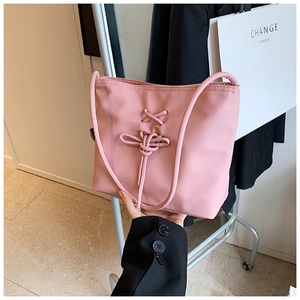Détail du sac seau rose avec un nœud décoratif en ruban et une finition lisse