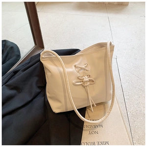 Détail du sac crème avec design à lacets croisés élégant et détails de franges
