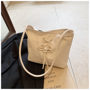 Détail du sac cabas crème avec lacets croisés décoratifs et œillets métalliques dorés