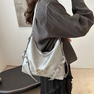 Grand sac à bandoulière argenté métallisé avec boucle nœud doré porté par un mannequin