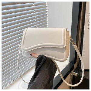 Close-up of the asymmetric wavy flap and gold hardware on this white crossbody bag