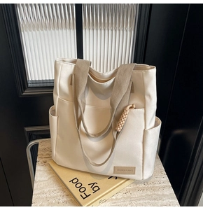 Macro shot of minimalist canvas tote bag with khaki straps and brand label on stone surface