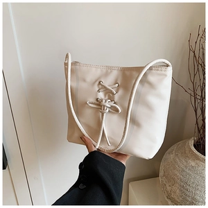 Détail du sac cabas blanc cassé avec décoration de ruban croisé et nœud minimaliste