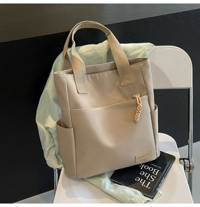 Close-up of beige canvas messenger bag on a white chair with stylish side pockets