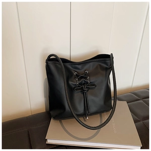 Détail du sac cabas noir avec un nœud décoratif et des œillets métalliques argentés