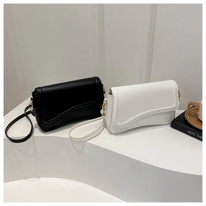 Close-up of minimalist square leather bags in black and white with wavy flap and gold hardware