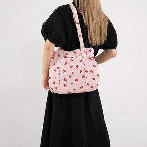 Pink corduroy tote bag with strawberry print and shoulder straps shown on model