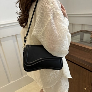 Minimalist black crossbody bag with curved flap design and golden hardware for women