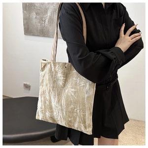 Detail of light gold velvet tote bag featuring elegant palm leaf patterns and leather straps