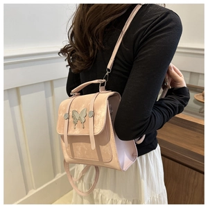 Pink suede backpack with silver butterfly charm shown on a model in a cozy setting