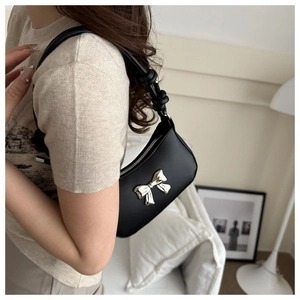 Close-up of black crescent shoulder bag with silver bow detail and knotted handle strap
