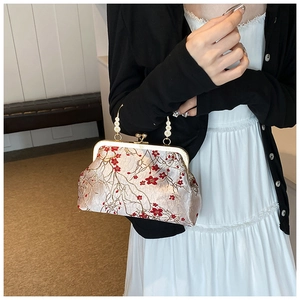 Detail of vintage champagne satin bag with red plum embroidery and pearl handle strap