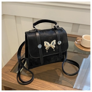 Detail of black vintage faux leather bag with large silver butterfly buckle decoration