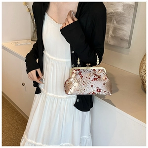 Detail of vintage floral embroidery and metallic kiss-lock clasp on the elegant handbag