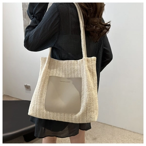 Detail of cream woven tote bag with faux leather pocket shown on model shoulder
