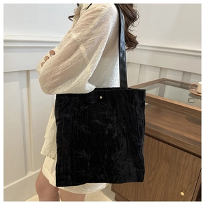 Close-up of black velvet tote bag with bamboo leaf texture and golden buckle detail