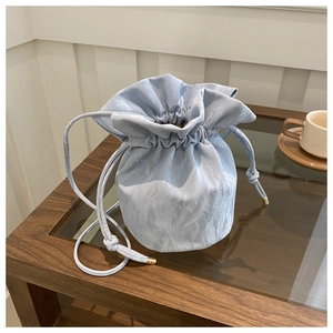 Close-up of light blue pleated drawstring bucket bag with elegant metal cord ends