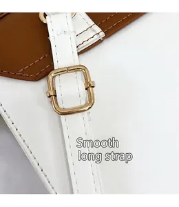 Detail der verstellbaren goldenen Metallschnalle am weiß-braunen Leder-Schultergurt