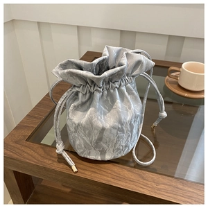 Detail view of silver bucket bag showing drawstring with premium gold metal ends