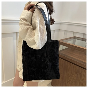 Detailed close-up showing the pleated velvet texture and smooth strap of this black tote bag