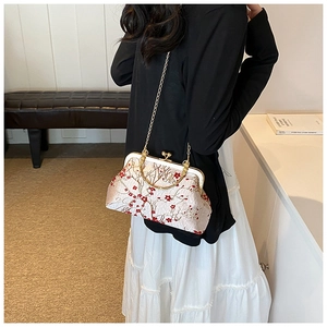 Detailed embroidery of red plum blossoms on a pink silk crossbody bag with metal handles