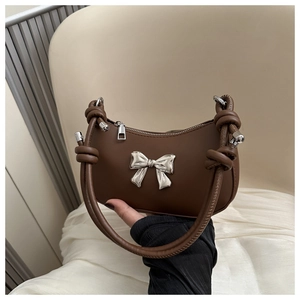 Close-up of brown crescent handbag with silver butterfly buckle and knotted strap