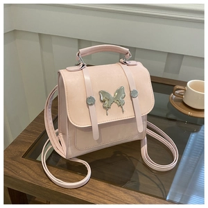 Detailed view of pink PU leather mini backpack featuring a metallic butterfly emblem
