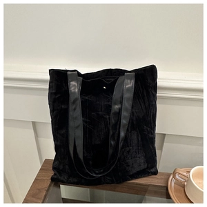 Detail view of large capacity black pleated velvet tote bag with sleek leather shoulder straps