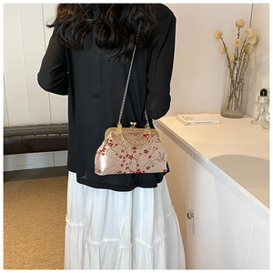 Macro shot of retro champagne silk kiss-lock bag with red and white plum blossom embroidery
