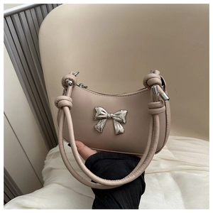 Detail of knot handle and silver metal bow on beige matte leather hobo bag