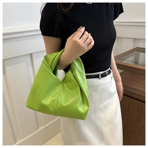 Detail of neon green pleated handbag featuring a unique knotted handle design