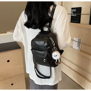 Detail of black mini PU leather backpack with cross-stitch pattern and monster charm