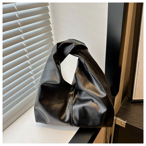 Close-up of a black pleated cloud bag featuring a unique knotted handle and soft faux leather texture