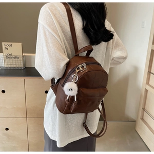 Detailed view of brown PU leather backpack with geometric texture and plush charm