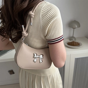 Minimalist beige crescent shoulder bag with silver bow detail and knotted strap accents