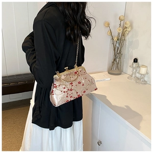 Detail of vintage champagne satin crossbody bag with red plum blossom embroidery and metal handle