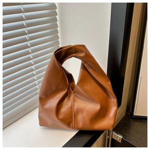 Detailed view of the caramel leather handbag featuring a unique knotted handle design