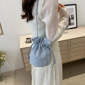 Minimalist light blue drawstring bucket bag with elegant pleated texture and shoulder strap