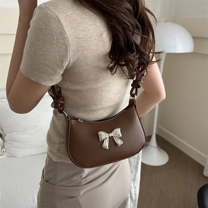 Brown leather crescent shoulder bag with silver bow accent and knotted strap detail